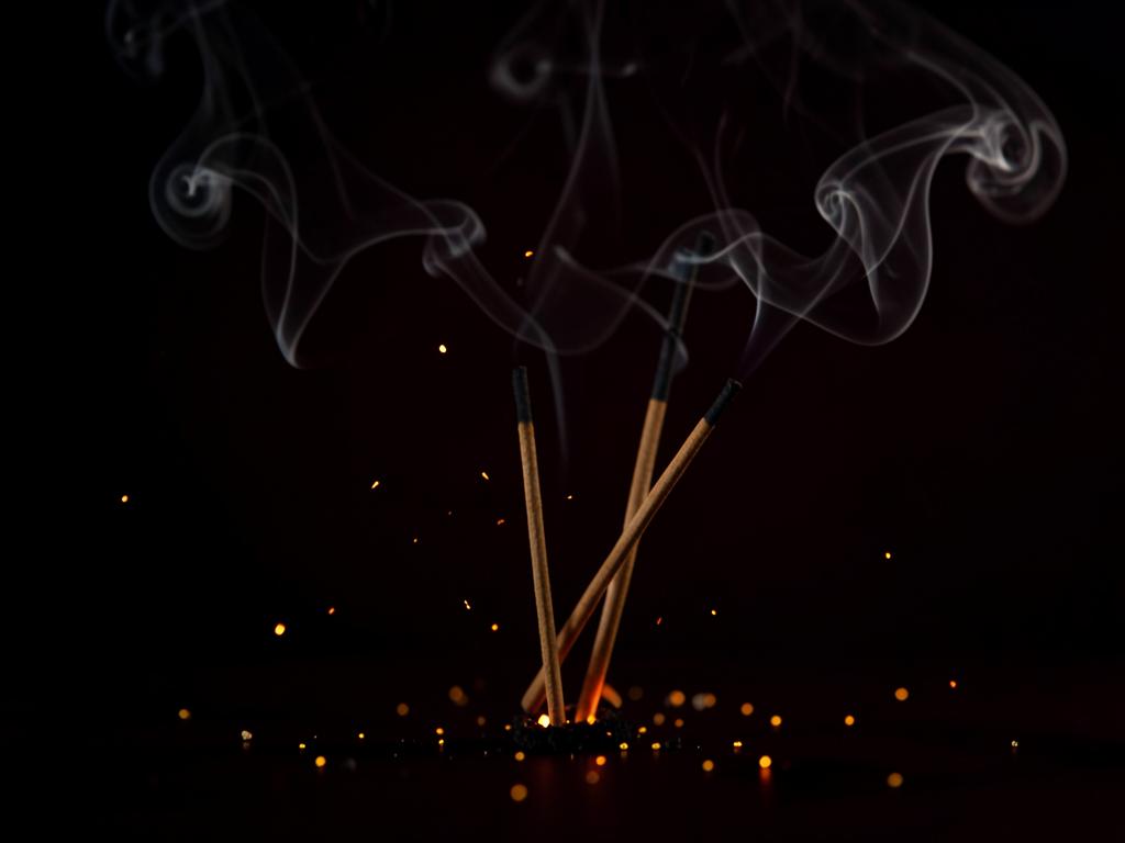 Incense sticks burning with soft trails of smoke